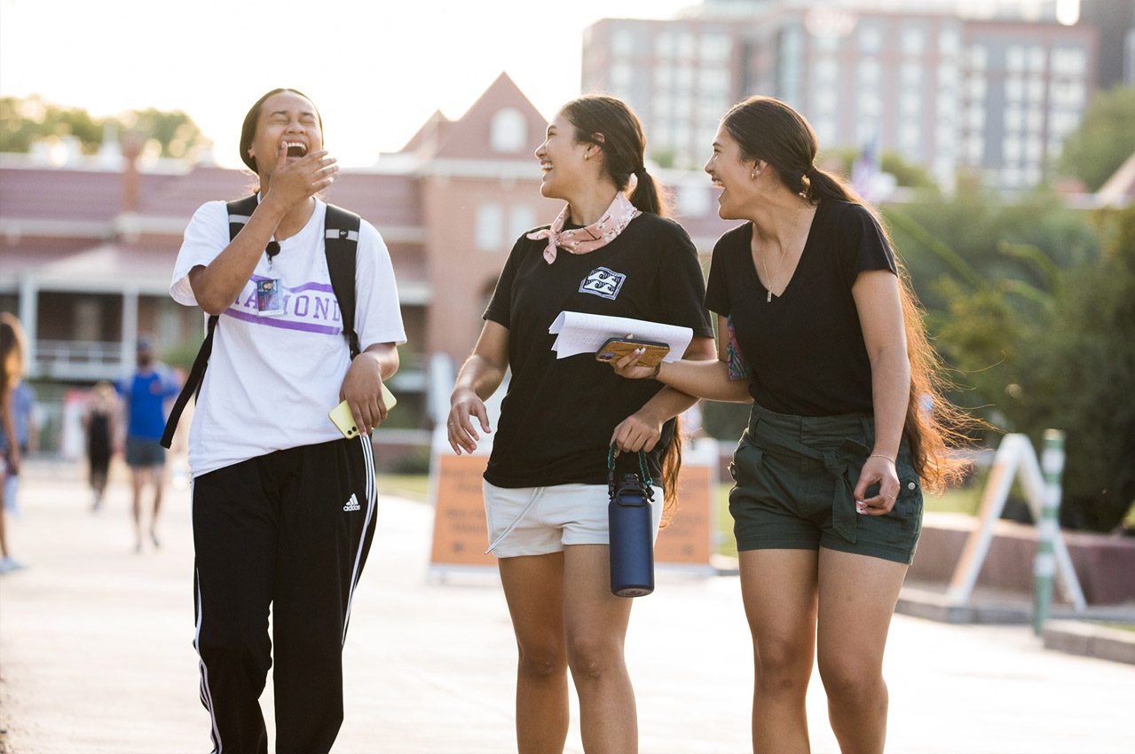 students laughing and walking on campus